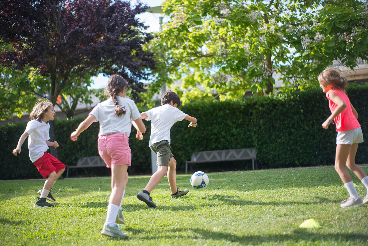 children playing soccer in the grass outside