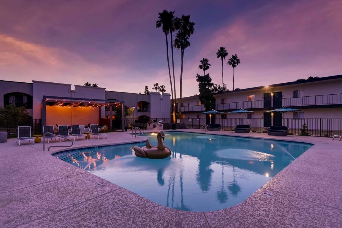 Pool with shaded deck seating and tall palm trees