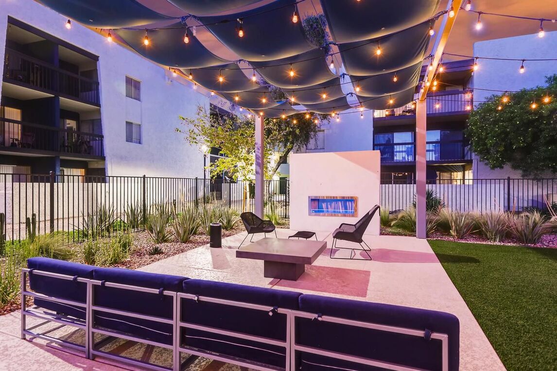 shaded deck next to the pool with sofas and chairs around a fire place