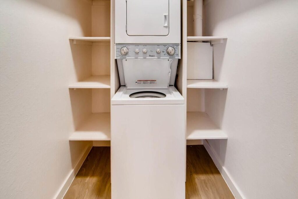 Laundry room with stacked washer and dryer and built in shelves