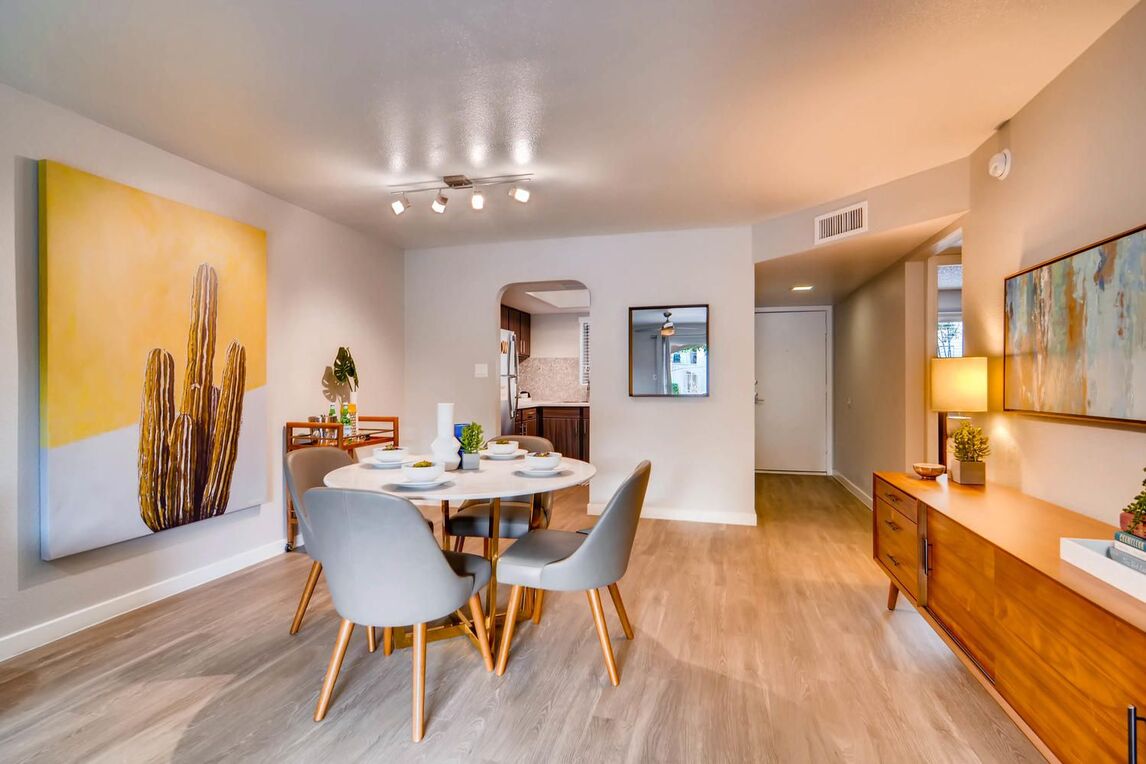 Dining Room area with circle table and 4 chairs. brown wooden TV stand and wall art