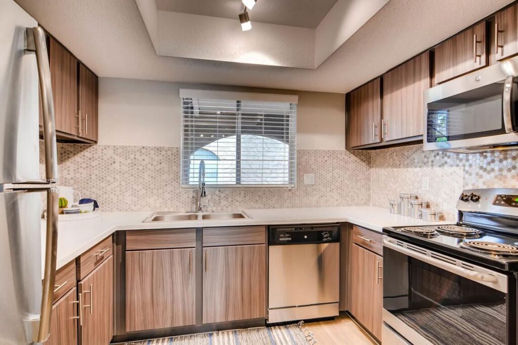 Kitchen with white counters, tile back splash and stainless steel appliances