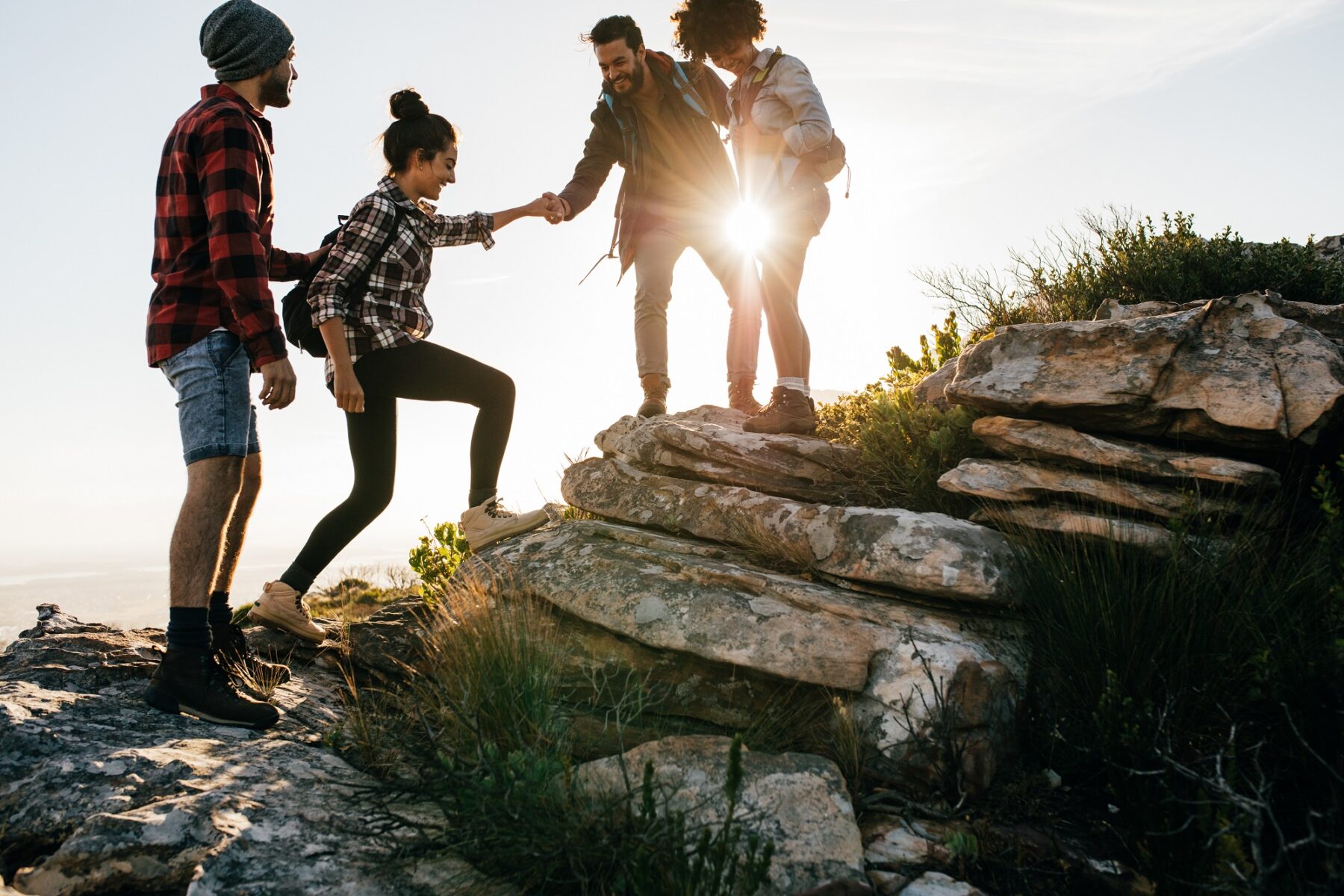 group of friends on a hike helping each other up the rocks